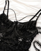 Black plus size lace bodysuit with floral lace, adjustable straps, and lace-up detail