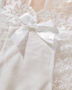 White lace babydoll lingerie with satin bow. Asymmetric design, low-rise thong, sensual wear.